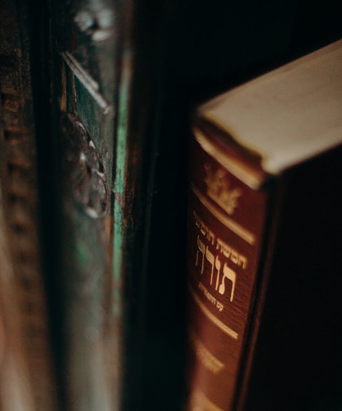 Close-up of a vintage Torah book with Hebrew text on a dark bookshelf, evoking tradition and wisdom.
